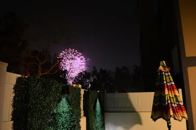 a firework display in the background with a fence and an umbrella at On the Doorstep in Anaheim