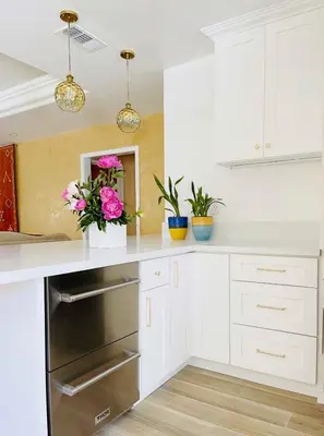 a kitchen with white cabinets and pink flowers on a counter at The Luxe Escape | Near LAX & West LA Hotspots in Los Angeles