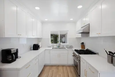 a white kitchen with white cabinets and a sink at The Luxe Escape | Near LAX & West LA Hotspots in Los Angeles