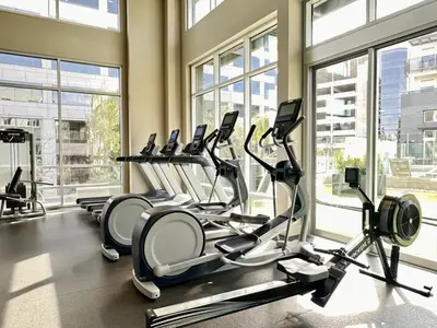 a gym with several treadmills in a room with windows at Tangerine Terrace -10 min to Disney&Angel Stadium in Orange