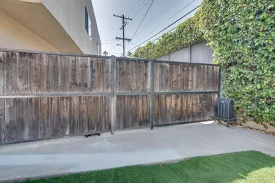 a wooden fence next to a yard with a hedge at 4 Mi to Hollywood Mid-Wilshire Couples Retreat in Los Angeles