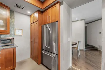 a kitchen with a stainless steel refrigerator and a table at Stylish Westwood Condo, Near UCLA & Century City in Los Angeles