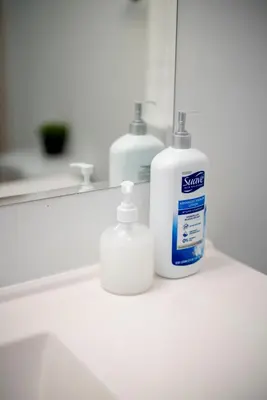 a bottle of soap sitting on a bathroom counter in front of a mirror at Cozy 2BR2BA Guest House in Alhambra in Alhambra