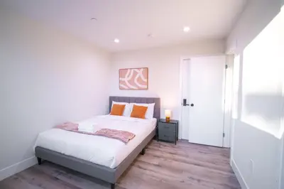 a bedroom with a bed with white sheets and orange pillows at Modern Private Ensuite Room near USC in Los Angeles