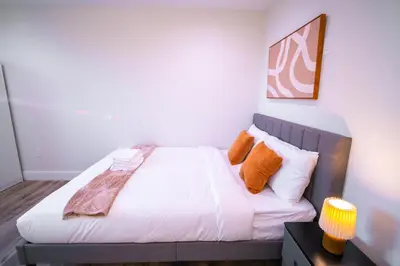 a bedroom with a bed with white sheets and orange pillows at Modern Private Ensuite Room near USC in Los Angeles