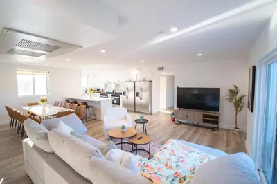 a living room with a large couch and a kitchen at Modern Private Ensuite Room near USC in Los Angeles