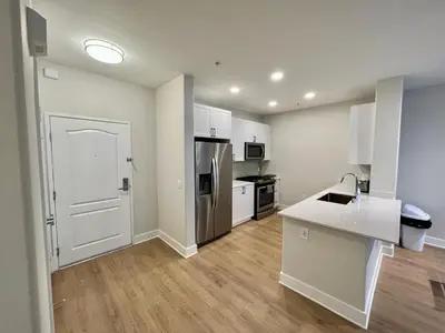 a kitchen with white cabinets and a white door at Miracle Mile Apartments in Los Angeles