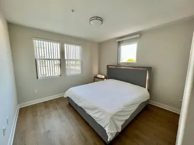 a bedroom with a bed and two windows at Miracle Mile Apartments in Los Angeles