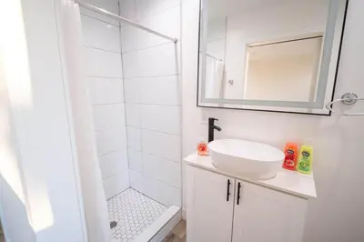 a white bathroom with a sink and a mirror at The Command Suite Urban Comfort Near USC in Los Angeles