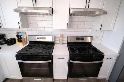 a kitchen with two stove tops and white cabinets at The Command Suite Urban Comfort Near USC in Los Angeles