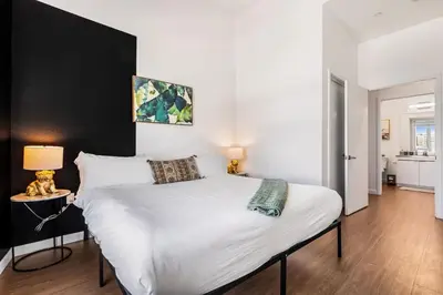 a bedroom with a white bed with a black wall at Central LA Hideaway, Steps from Japanese Village in Los Angeles