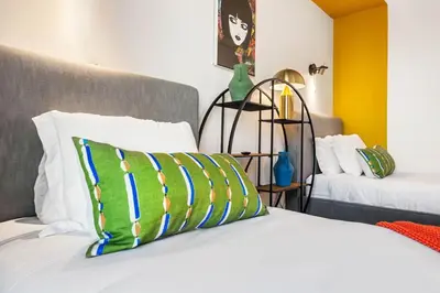 a bed with a green and blue pillow on it at 2BD 2BA Stylish Arts District Retreat, Walk to Little Tokyo in Los Angeles