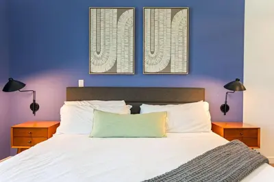 a bedroom with a white bed with two night stands at Modern Studio Retreat in the Heart of Art District in Los Angeles