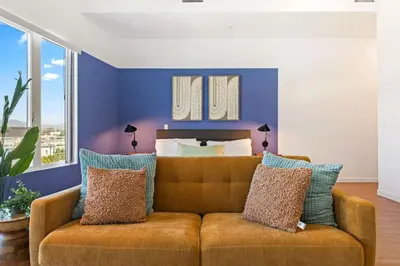 a living room with a couch in front of a bed at Modern Studio Retreat in the Heart of Art District in Los Angeles