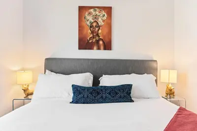 a bedroom with a white bed with a painting above it at Arts District Condo, Walk to Little Tokyo Plaza in Los Angeles