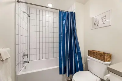 a bathroom with a blue shower curtain and a toilet at Stylish 2BD Haven with Scenic DTLA Views and Parking in Los Angeles