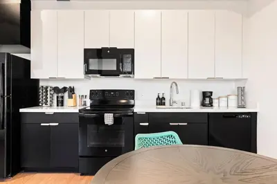 a kitchen with black and white cabinets and a table at Chic Studio with Stunning DTLA Views, Walk to Metro in Los Angeles