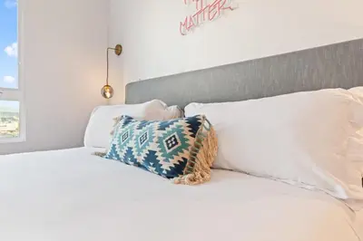 a white bed with a pillow on top of it at Chic Studio with Stunning DTLA Views, Walk to Metro in Los Angeles