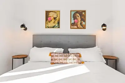 a bedroom with a white bed with two pictures on the wall at Spacious 1-BD with Stunning City Views in DTLA in Los Angeles