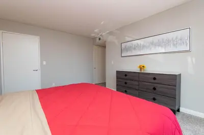 a bedroom with a red bed and a dresser at Modern Hollywood Apt Rooftop Pool & Skyline Views in Los Angeles