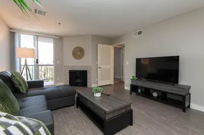 a living room with a couch and a flat screen tv at Stylish 2BR Apt with Rooftop Pool & Hollywood Views in Los Angeles