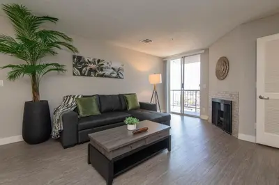 a living room with a couch and a palm tree at Stylish 2BR Apt with Rooftop Pool & Hollywood Views in Los Angeles