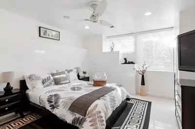 a white bedroom with a bed and a flat screen tv at Quiet Home with Spectacular Scenic Mountain Views near Universal Studios Hollywood in Los Angeles