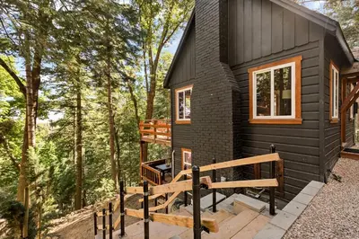 a black tiny house in the woods at Cute Romantic Cabin With Hot Tub 5 Min from Lake in Crestline