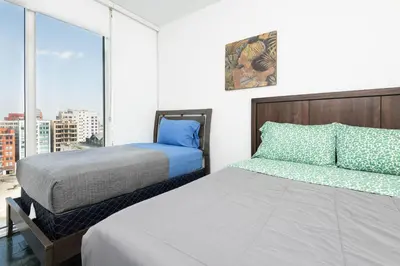 a bedroom with two beds and a large window at Stunning 3BR High Rise Pool, Spa & Rooftop Views in Los Angeles