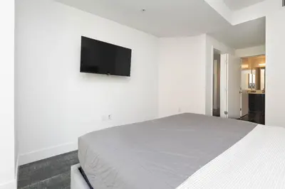 a white bedroom with a bed and a flat screen tv at Stunning 3BR High Rise Pool, Spa & Rooftop Views in Los Angeles