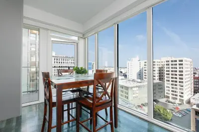 a dining room with a table and chairs and large windows at Stunning 3BR High Rise Pool, Spa & Rooftop Views in Los Angeles