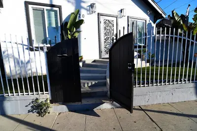a black gate in front of a house with stairs at Urban Oasis in Los Angeles