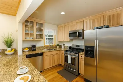 a kitchen with stainless steel appliances and wooden cabinets at Cozy Cabin with Large Backyard Near Lake, Village and Snow Summit in Big Bear Lake