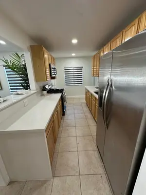 a kitchen with a stainless steel refrigerator and wooden cabinets at Coastal Calm Casita in Long Beach