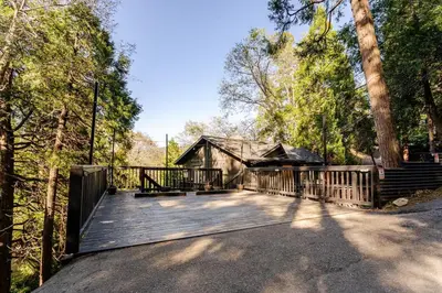 a wooden deck with a house in the woods at Sleeps 10 Cozy Modern Cabin 4 bedroom 3 bath 2400 sq ft 3 story Updated Quiet cabin in Crestline