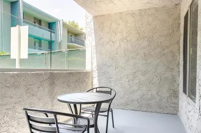 a table and chairs on a patio with a building at Blueground Pasadena pool nr Pasadena Park LAX-1391 in Los Angeles