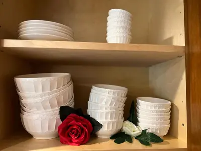 a shelf with white plates and a rose on it at Cozy Cabin in Crestline