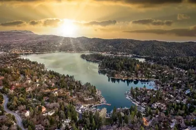 an aerial view of a lake with the sun setting at Koda House in Lake Arrowhead