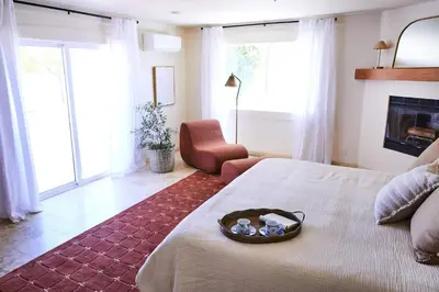 a bedroom with a bed and a chair and windows at Oja Mountain Ridge in Ojai