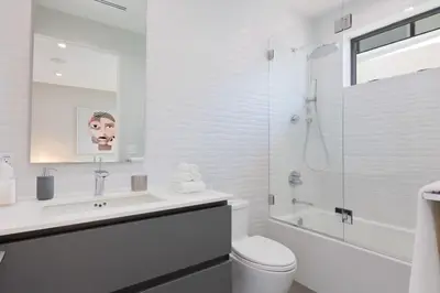 a white bathroom with a toilet and a shower at The Artezen Villa by Stay Awhile Villas in Los Angeles