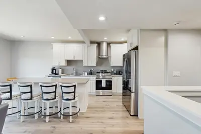 a kitchen with white cabinets and a island with bar stools at Seaspray at Anacapa View in Port Hueneme