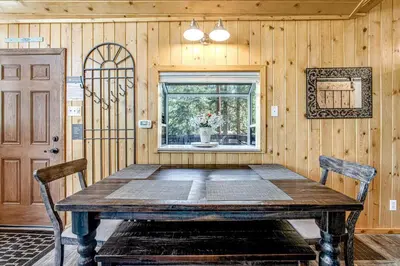 a dining room with a wooden table and a window at Castle Rock Cabin #1 ~ Comfortable cabin with modern amenities and deck - near hiking and lake in Big Bear Lake