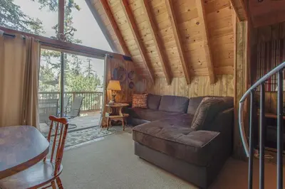 a living room with a couch and a balcony at Castle Rock Cabin #2 ~ Cozy cabin close to Fisher Cove & Boulder Bay - short drive to skiing in Big Bear Lake