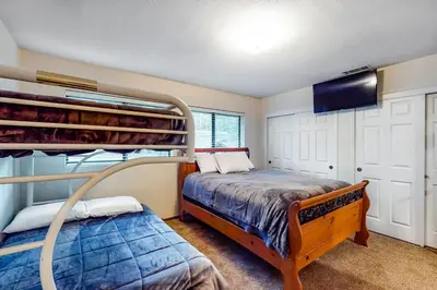 a bedroom with two bunk beds and a flat screen tv at Rosie's Hideaway ~ Spacious Retreat Near the Mountain & Lake with Grill & Full Kitchen in Big Bear Lake