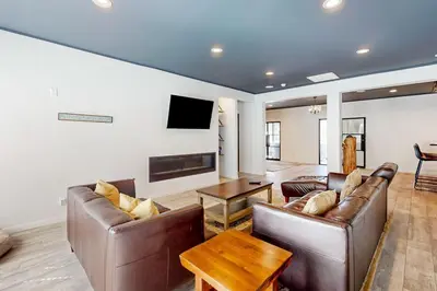 a living room with two leather couches and a tv at Hillside Hideaway ~ Dog-friendly home with wraparound deck, grill, game room, & bar - walk to dining in Big Bear Lake