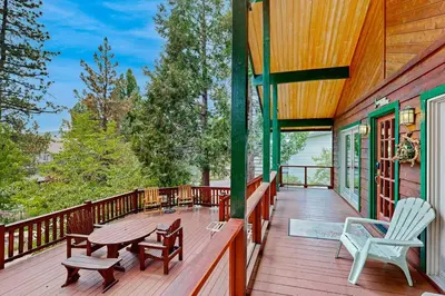a wooden deck with a table and chairs on it at Rooster's Den ~ Charming house with expansive deck, cable, internet, near Big Bear Lake in Big Bear Lake