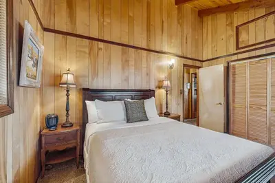 a bedroom with a bed in a wooden wall at Idle Ours Cabin ~ Rustic and Cozy Cabin with Fireplace & Private BBQ - Walk to Big Bear Lake in Fawnskin