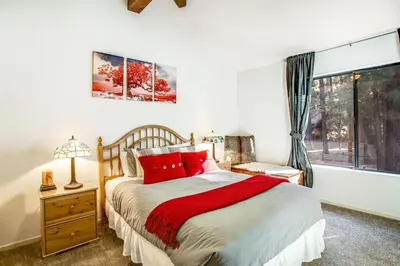 a bedroom with a bed with red pillows and a window at Summit Hideaway ~ Fantastic Mountain getaway with private hot tub, free Wi-Fi, full kitchen, & more in Big Bear Lake