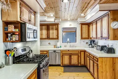 a kitchen with wooden cabinets and a stove top oven at Summit Hideaway ~ Fantastic Mountain getaway with private hot tub, free Wi-Fi, full kitchen, & more in Big Bear Lake