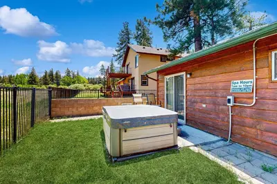a hot tub sitting in the yard next to a house at Meadow-Front Metcalf Bay Cabin Hot Tub, Air Hockey, Firepit & Lake Views in Big Bear Lake
